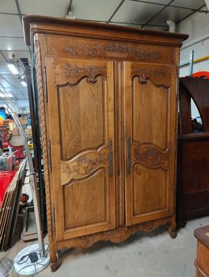 a wooden armoire in the middle of a room filled with furniture