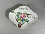 une petite assiette sur laquelle sont peints un oiseau et des fleurs