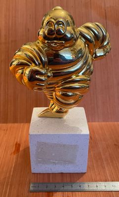 statue en or représentant un homme qui rit, posée sur un bloc de marbre