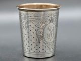 an old silver cup sitting on top of a table next to a knife