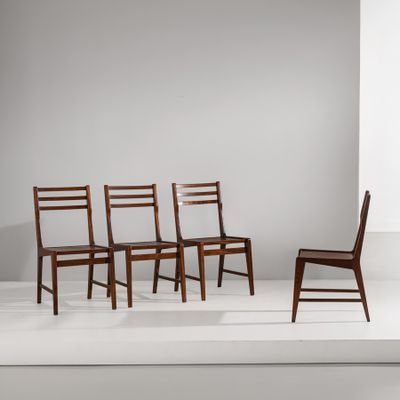 quatre chaises en bois sont disposées sur une estrade blanche devant un mur blanc