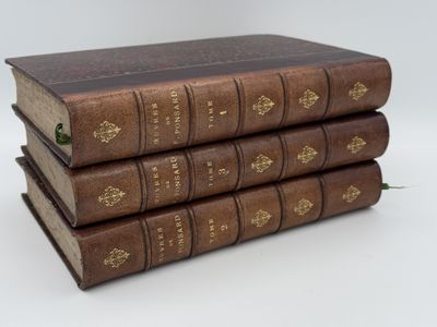 trois vieux livres empilés sur une surface blanche