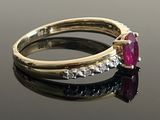 a close up of a gold ring with a ruby stone and diamonds