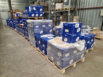 Des cartons de papier toilette sont empilés sur des palettes dans un entrepôt