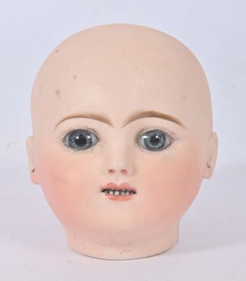 une tête de poupée aux grands yeux posée sur une surface blanche