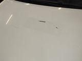 the hood of a white car with a hole in the hood