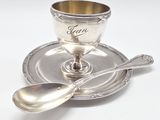an antique silver cup and saucer with spoon on a saucer