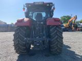 a red tractor parked in a parking lot next to a building