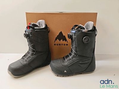 the snowboard boots are next to the box on the table