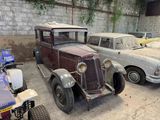 several old cars are parked in a garage next to a brick wall
