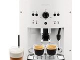 a white coffee machine with two cups of coffee next to it