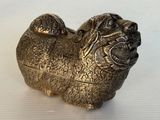 une figurine de chien en argent posée sur une surface blanche