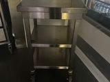 a stainless steel table in a kitchen with a refrigerator in the background