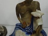 a statue of a man sitting on a rock with a dog
