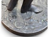 a bronze statue of a person standing on a coin