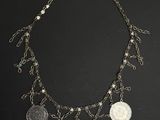a close up of a necklace with coins on a black background