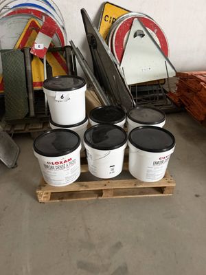 plusieurs seaux de peinture posés sur une palette près d'un mur