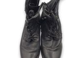 une paire de bottes en cuir noir à lacets posées sur une surface blanche