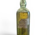 an old bottle of liquor sitting on top of a white surface
