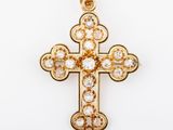 a gold and diamond cross pendant on a white background
