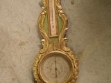 une horloge dorée posée par terre, avec un cadran vert
