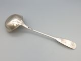 une cuillère en argent dont le manche repose sur une table