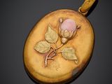une image représentant un pendentif en forme de rose dorée et rose sur fond noir