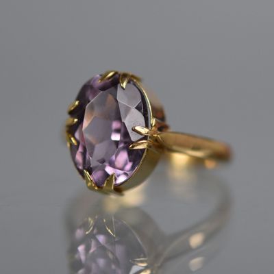 gros plan d'une bague en or avec une pierre violette