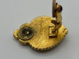 a close up of a gold pin with a bird on it