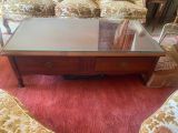 une table basse avec un plateau en verre posée sur un tapis rouge
