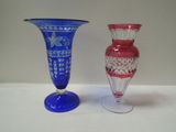 two glass vases sitting on a table next to each other
