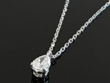 silver necklace with a tear shaped diamond on a black surface