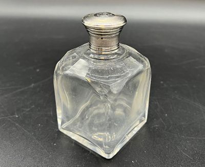 une petite bouteille en verre avec un bouchon argenté posée sur une table