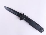 un couteau noir avec un manche noir posé sur une surface blanche