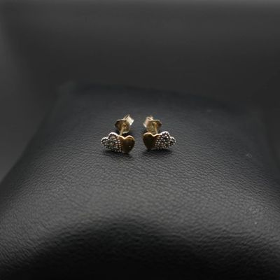 une paire de boucles d'oreilles en or posées sur une surface en cuir noir