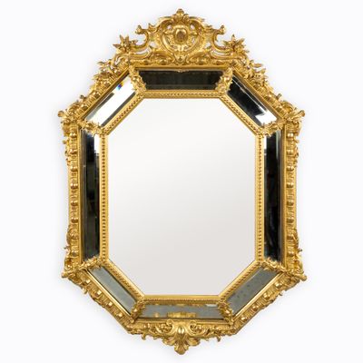 un miroir doré richement décoré, bordé d'une moulure noire et blanche