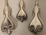 four silver spoons are lined up on a white surface