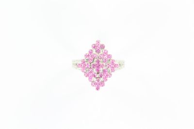 une photo d'une bague sertie d'un diamant rose posée sur une surface blanche
