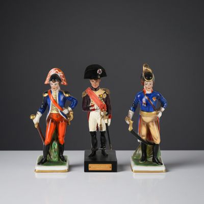 trois figurines représentant des hommes en uniforme militaire posées sur une surface blanche