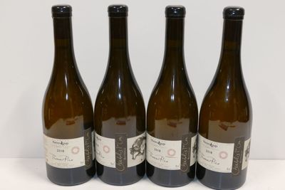 quatre bouteilles de vin sont alignées sur une surface blanche