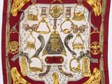 une écharpe carrée rouge et dorée sur laquelle figurent divers objets