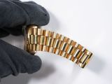 a person wearing gloves holding a gold watch band