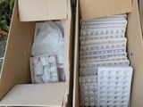 plusieurs cartons contenant des objets divers, posés par terre devant un immeuble