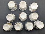 twelve cups and saucers are arranged in a circle on a table