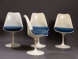 three tulip chairs with blue cushions in a row on a gray surface