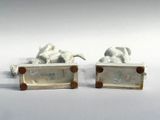 two figurines of elephants on display on a white surface