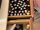 a desk with a drawer full of cosmetics and a laptop