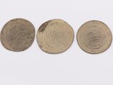 three coins are shown in a row on a white surface