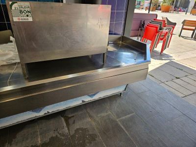 a stainless steel bench on the sidewalk in front of a building