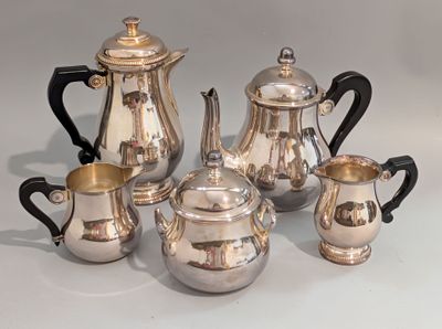 un service à thé en argent posé sur une table, à côté d'autres objets en argent